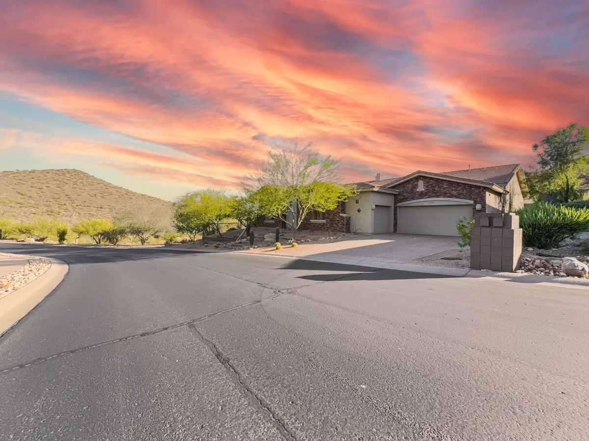 A wide exterior shot of the house with the driveway in the foreground and gentle surrounding hills and sky in the background. The scene captures the privacy and tranquility of the setting, with hints of nearby trails and expansive outdoor areas for exploration and relaxation.