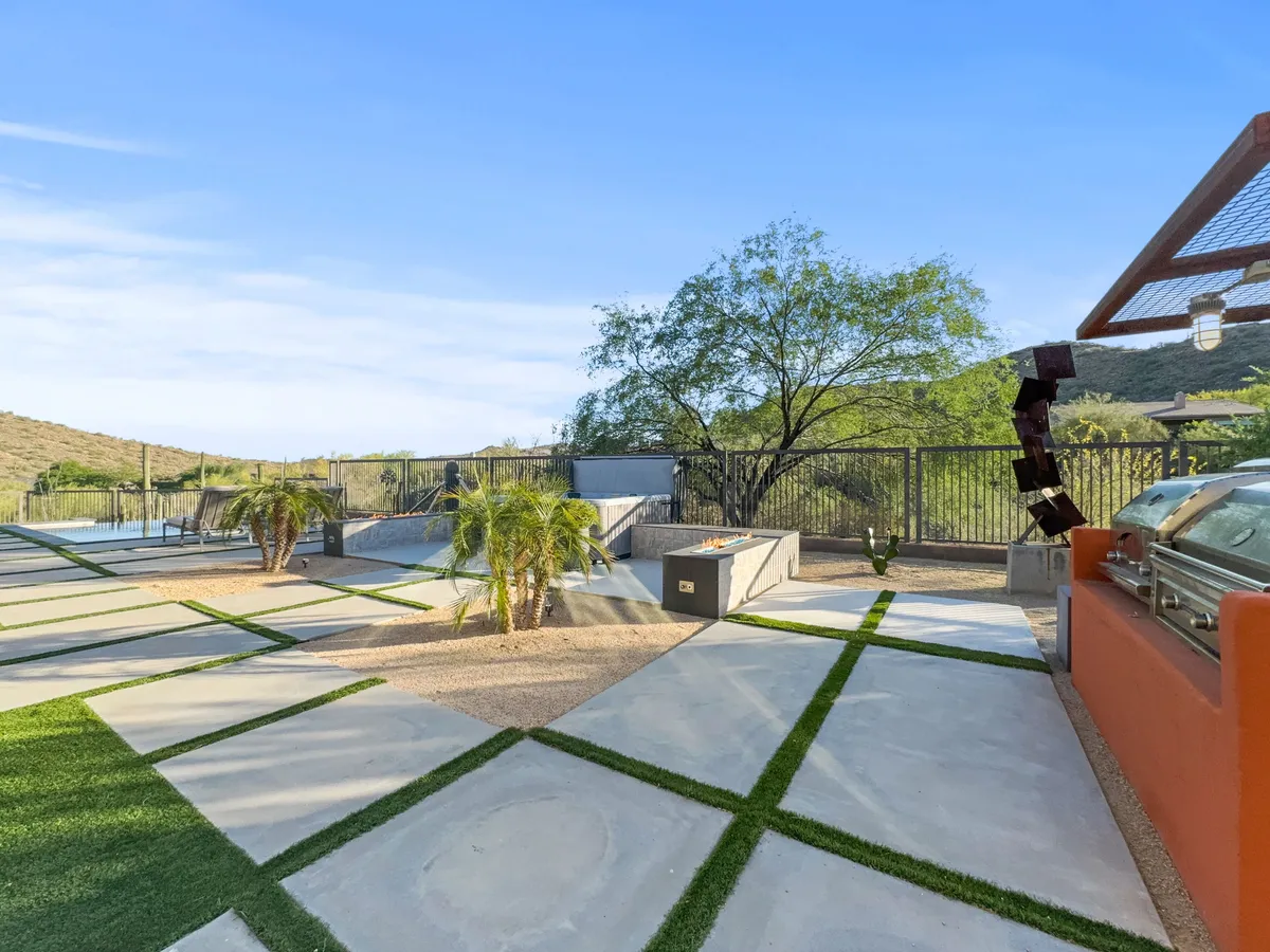 A modern outdoor grilling area surrounded by palm trees and landscaped pathways, perfect for preparing meals outside. The setting is relaxed and inviting, ideal for gatherings and al fresco dining.