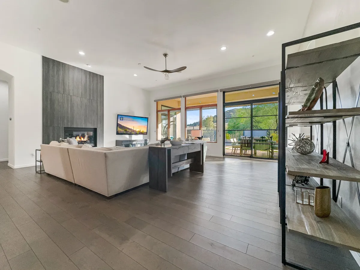 A spacious, modern living room with a sleek sofa, fireplace, large windows, and a TV. The room is flooded with natural light and offers a cozy yet refined atmosphere for relaxation and entertaining.