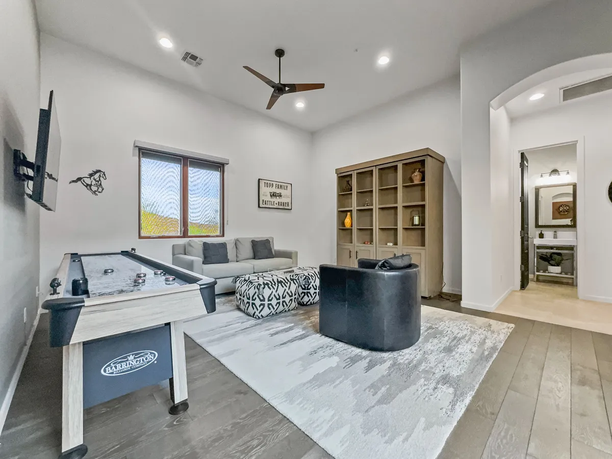 A stylish game room featuring a pool table, comfortable sofa, shelving, and vibrant artwork. The space radiates energy and invites guests to play, relax, and socialize.